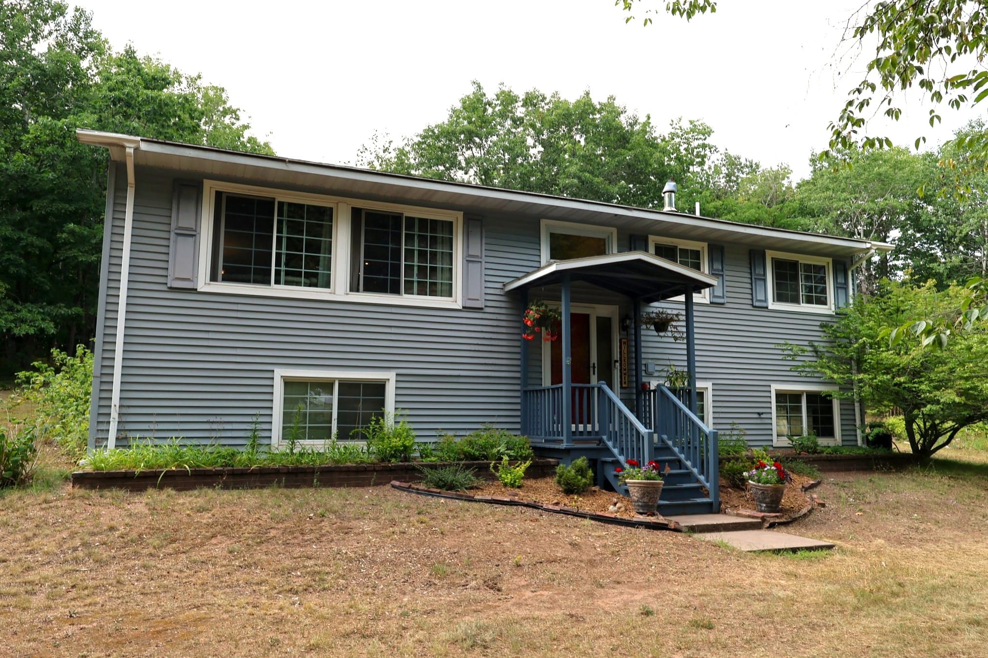 1501 N 5th Ave W, Washburn WI, blue split-entry home with covered front porch on 1.57 wooded acres.