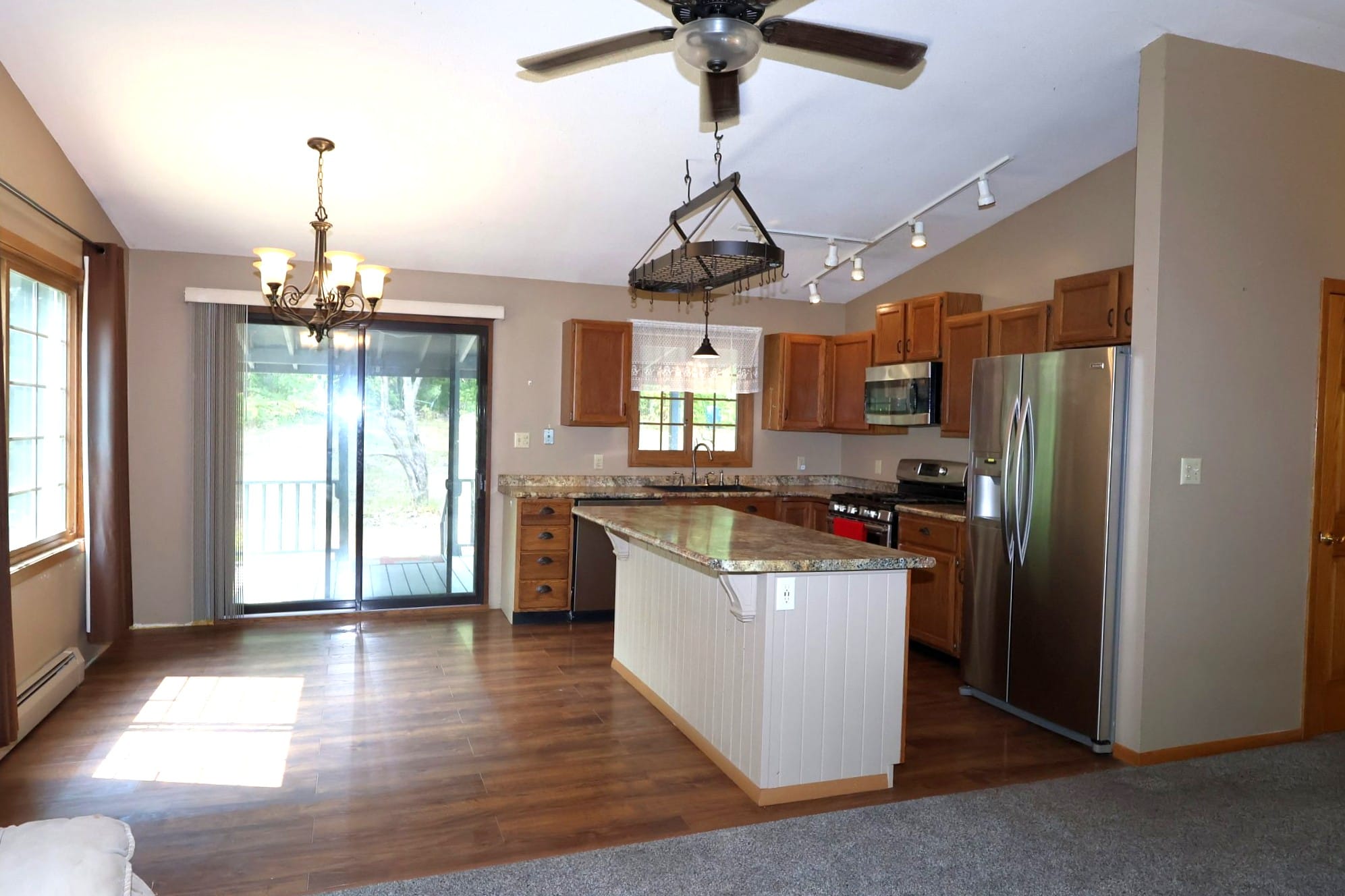 Kitchen and dining area at 1501 N 5th Ave W, Washburn WI, with vaulted ceilings, center island, stainless appliances, and patio doors to the deck.