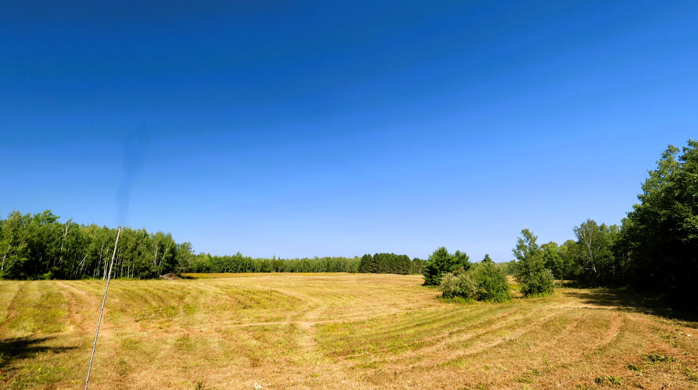 33XXX Old County Hwy K, Bayfield WI, open hay field with panoramic views and a wooded treeline on 70 acres.