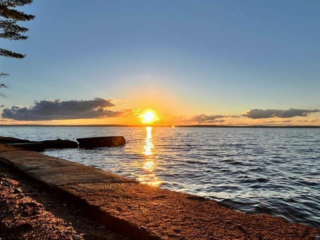 Sunset over Lake Superior from the grandfathered concrete break wall at 55161 Corbine Rd in Ashland, WI, with the walkable concrete edge running along the water and the far shore of Chequamegon Bay on the horizon.